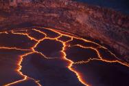 Incandescent lines mark the boundaries between migrating crustal plates on the surface of the lava lake in HALEMAUMAU crater.  Here, and at other lava lakes across the world, these rifting zones have a characteristic zigzag pattern.  