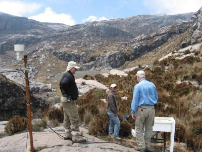 USGS and INGEOMINAS colleagues at an lahar-detection (Acoustic Flow Monitor or AFM) station on the west flank of Nevado del Ruiz, Colombia. View is up the glacial valley toward the summit area. (Click image to view full size.)